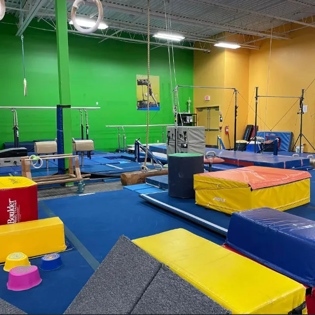 A vibrant gymnastics gym with colorful equipment, including mats, rings, and balance beams, ready for athletes to practice their routines.