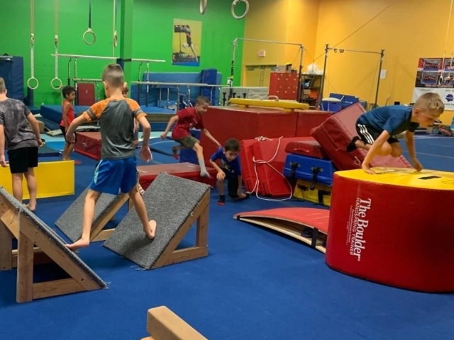 Children actively participating in an obstacle course at a gymnastics center, showcasing agility and coordination.